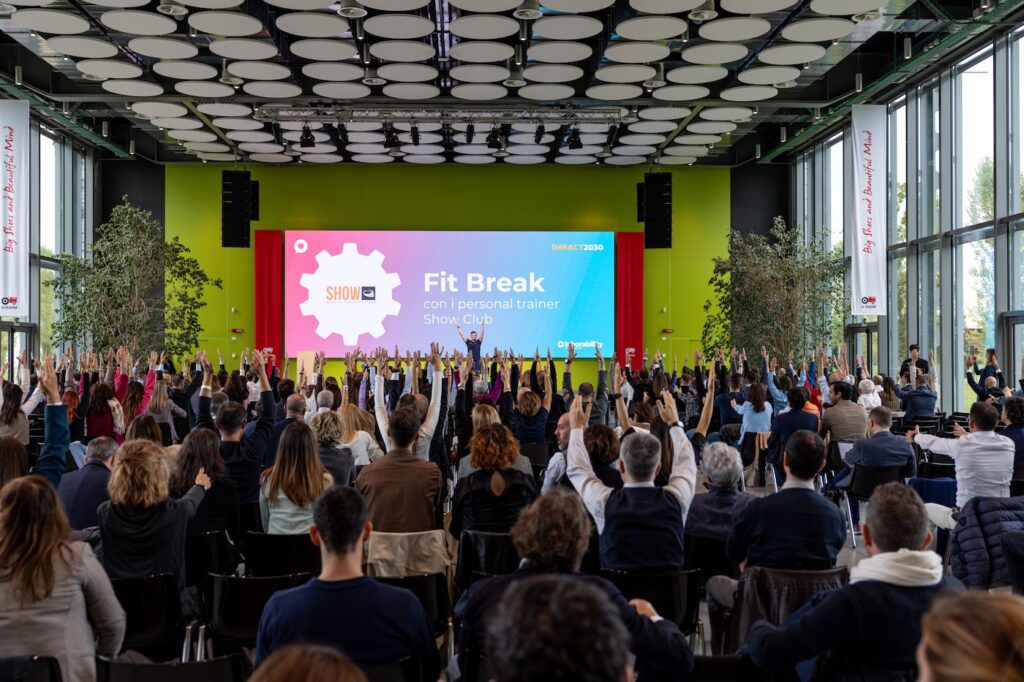 Show Club Personal Trainer sul palco di IMPACT2030 fa fare degli esercizi alla platea